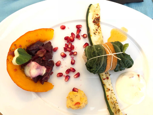 Nett angerichteter Teller mit Kürbis, Granatapfelkernen, Zucchini und eine leckere vegane Kohlroulade